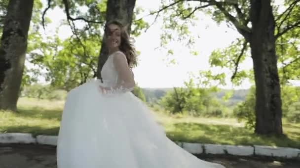 Hermosa y encantadora novia en vestido de novia corriendo en el parque. Movimiento lento — Vídeo de stock