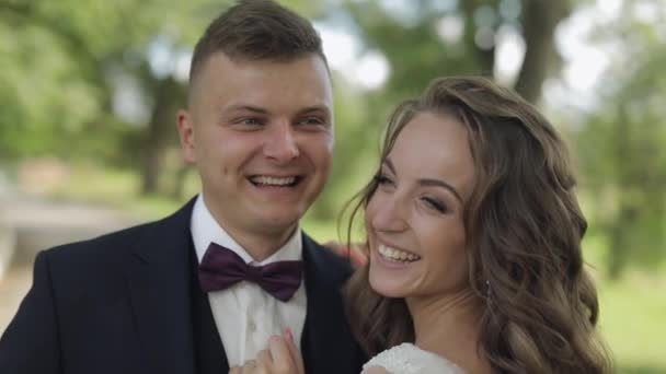Kaukasiska brudgummen med bruden skrattar i parken. Bröllopspar. Lyckliga nygifta — Stockvideo