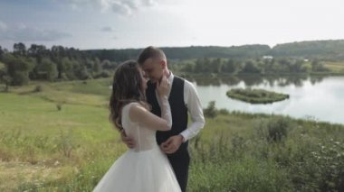 Göl kenarındaki parkta gelinli beyaz damat. Düğün çifti. Yeni evliler öpücük
