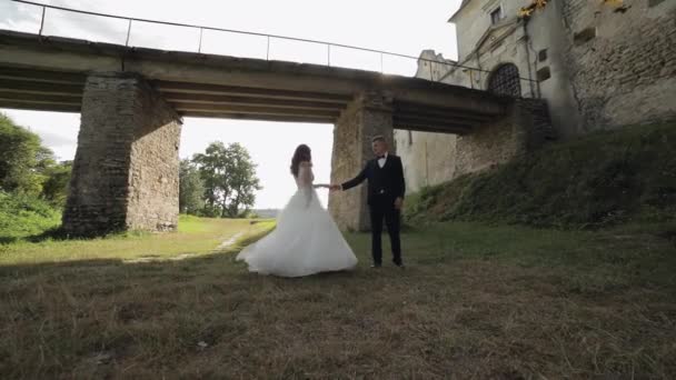 Наречений з нареченою танцює біля старого замкового мосту. Весільна пара. молодята — стокове відео