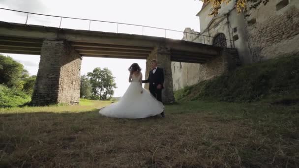 Novio con novia bailando cerca del viejo puente del castillo. Pareja de bodas. Recién casados — Vídeo de stock