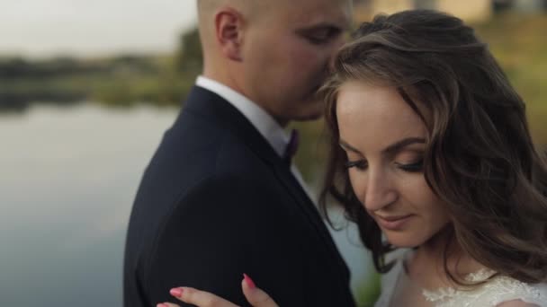 Novio caucásico con novia en el parque cerca del lago. Pareja de bodas. Recién casados beso — Vídeos de Stock