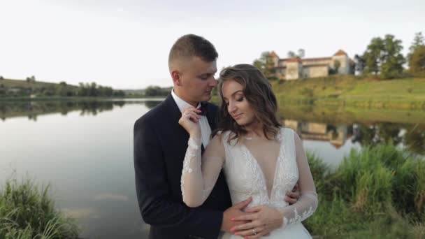 Pengantin pria kaukasia dengan pengantin wanita di taman dekat danau. Pasangan pernikahan. Ciuman pengantin baru — Stok Video