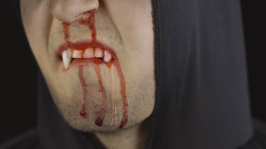 Erkek vampir Cadılar Bayramı makyajı ve kostümü. Yüzünde kan olan bir adam.