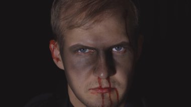 Cadılar Bayramı erkek portresi. Yüzünden kan damlayan bir adam. Korkunç makyaj.