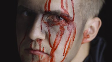Cadılar Bayramı erkek portresi. Yüzünden kan damlayan bir adam. Korkunç makyaj.
