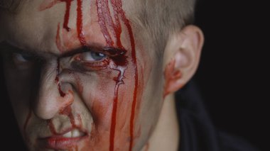 Cadılar Bayramı erkek portresi. Yüzünden kan damlayan bir adam. Korkunç makyaj.