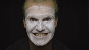 Cadılar Bayramı palyaço portresi. Şeytani bir palyaçonun yüzüne yakın çekim. Beyaz yüz makyajı