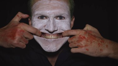 Cadılar Bayramı palyaço portresi. Şeytani palyaçolar. Parmaklarıyla korkunç bir gülümseme