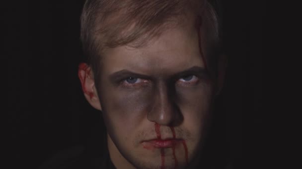 Retrato de Halloween. Un tipo con sangre goteando en su cara. Maquillaje aterrador — Vídeos de Stock