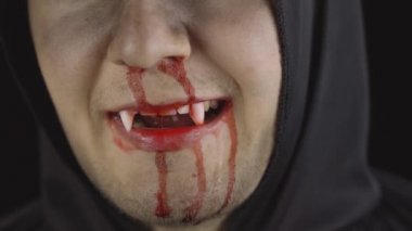 Erkek vampir Cadılar Bayramı makyajı ve kostümü. Yüzünde kan olan bir adam.