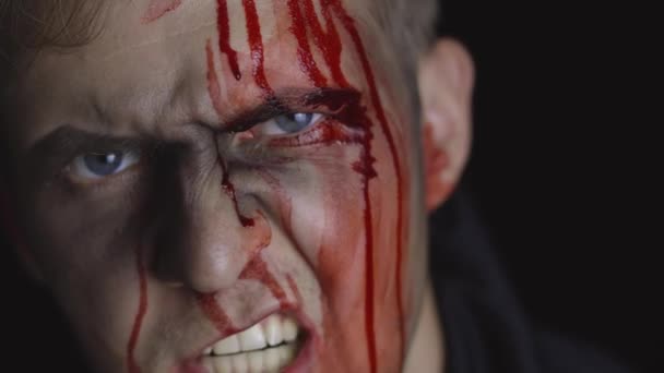 Retrato de Halloween. Un tipo con sangre goteando en su cara. Maquillaje aterrador — Vídeos de Stock