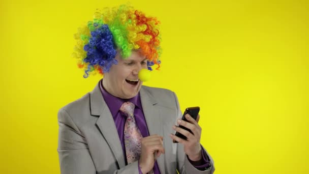 Clown businessman entrepreneur in wig using app on smartphone for online work — Stock Video