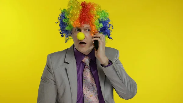 Clown businessman entrepreneur boss talking on mobile phone. Yellow background — Stock Photo, Image