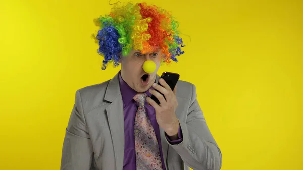 Clown businessman entrepreneur in wig using app on smartphone for online work — Stock Photo, Image