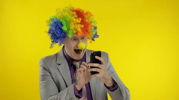 Clown businessman entrepreneur in wig using app on smartphone for online work — Stock Photo, Image