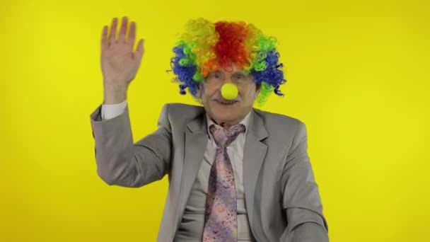 Senior elderly clown businessman entrepreneur in wig waves his hands, smiling — Stock Video