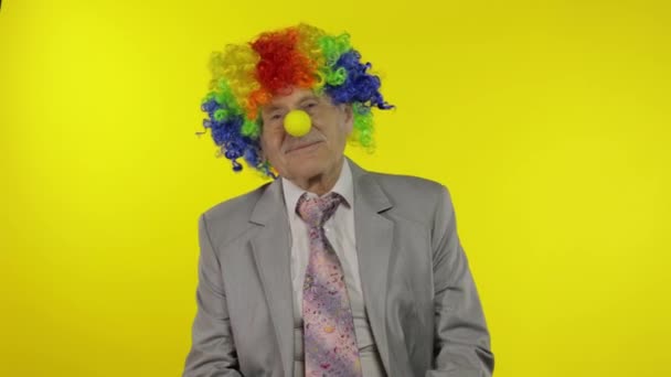 Senior elderly clown businessman entrepreneur boss in wig adjusts yellow nose — Stock Video