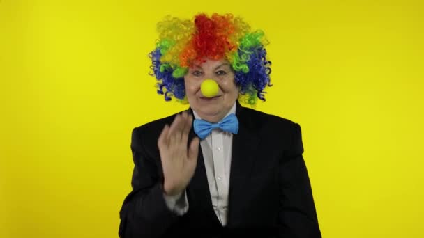 Vieille femme clown en perruque agite les mains, souriant. Fond jaune — Video