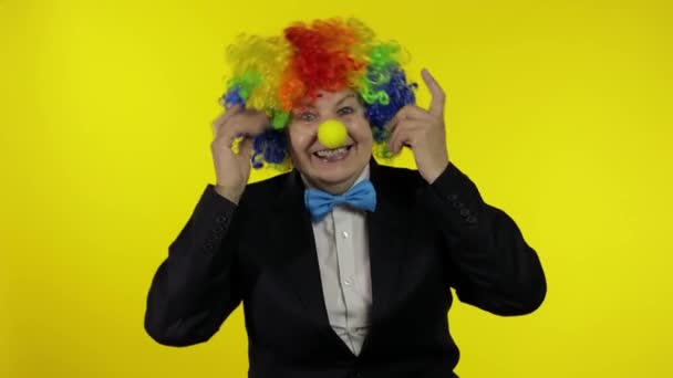 Senior old woman clown in colorful wig smiling, making silly faces, fool around — Stock Video