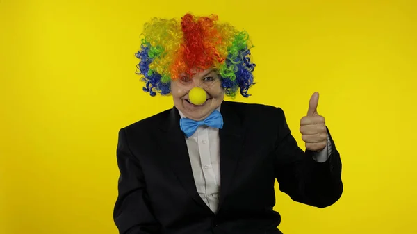 Senior woman clown in wig having fun, smiling, show thumb up. Halloween