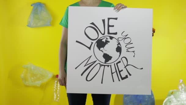 Mujer irreconocible sosteniendo cartel protestando Ama a tu Madre Tierra. Medio ambiente contaminación plástica — Vídeos de Stock