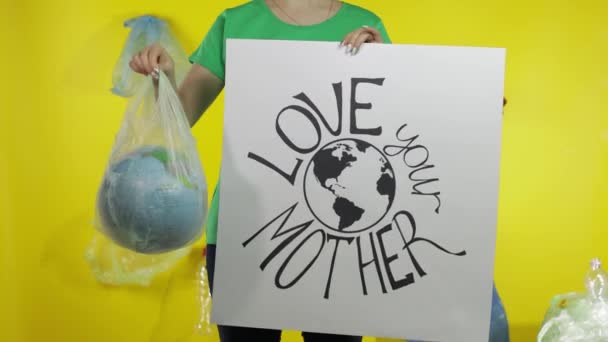 Mujer irreconocible con cartel de protesta y globo terráqueo en paquete de plástico. Contaminación ecológica — Vídeo de stock