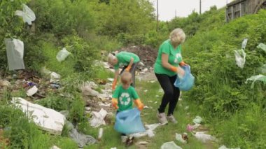 Eko tişörtlü doğa aktivistleri parkta plastik çöp topluyor. Geri dönüşüm, toprak kirliliği