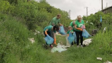Eko tişörtlü doğa aktivistleri parkta plastik çöp topluyor. Geri dönüşüm, toprak kirliliği