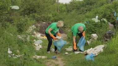 Gönüllü ekip plastik torbalar ve şişelerden kirli parkı temizliyor. Çöp selofan kirliliğini azaltır