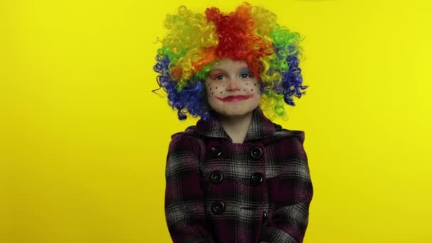 Pequena criança palhaço menina em peruca colorida fazendo caras bobas, olha com olhos em direções diferentes — Vídeo de Stock