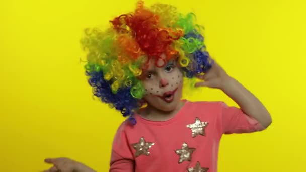 Kleines Kindermädchen Clown mit Perücke macht dumme Gesichter. Spaß haben, lächeln, Zunge zeigen. Halloween — Stockvideo