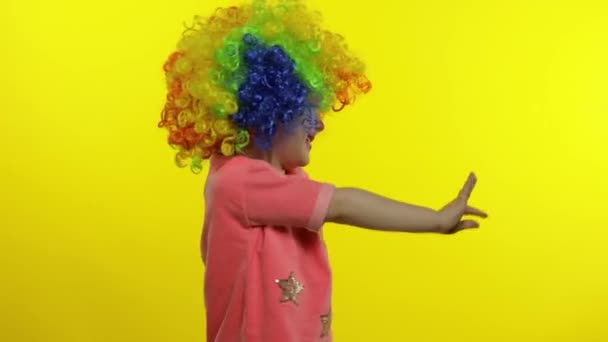 Маленька дівчинка клоун в барвистій перуці махає руками, розважається, посміхається. Хеллоуїн — стокове відео