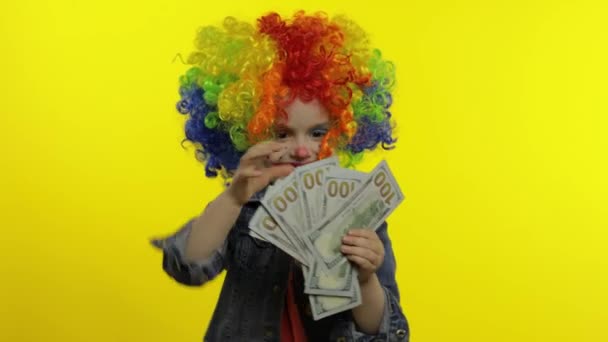 Niña payaso en peluca haciendo caras tontas, divirtiéndose con billetes de dinero en efectivo dólar — Vídeo de stock