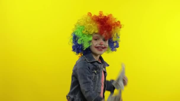 Payaso de niña en peluca colorida bailando con billetes de dinero en efectivo. Divertirse, sonreír — Vídeo de stock