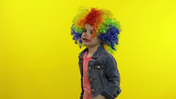 Pequena criança palhaço menina em peruca colorida fazendo caras bobas. A divertir-se, a sorrir, a dançar. Halloween. — Vídeo de Stock