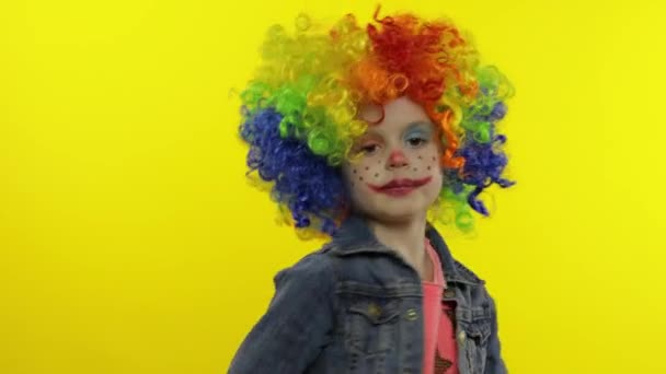 Lille barn pige klovn i farverig paryk gør fjollede ansigter. Have det sjovt, smile, danse. Halloween – Stock-video