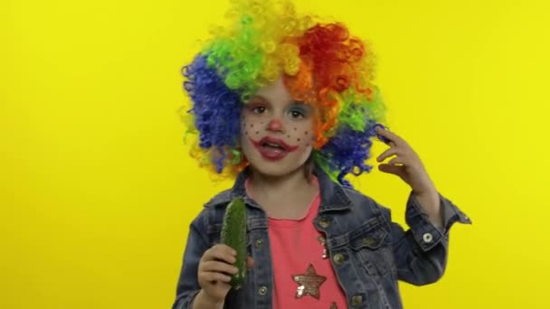 Pikkutyttö pelle värikkäässä peruukissa, irvistelee, laulaa, hymyilee, tanssii. Halloween — kuvapankkivideo