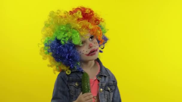 Niña payaso en peluca colorida haciendo caras tontas, cantando, sonriendo, bailando. Halloween — Vídeo de stock