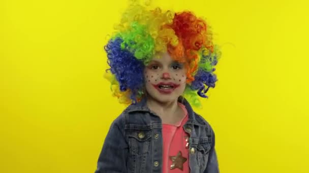 Lille barn pige klovn i farverig paryk gør fjollede ansigter, sang, smil, dans. Halloween – Stock-video