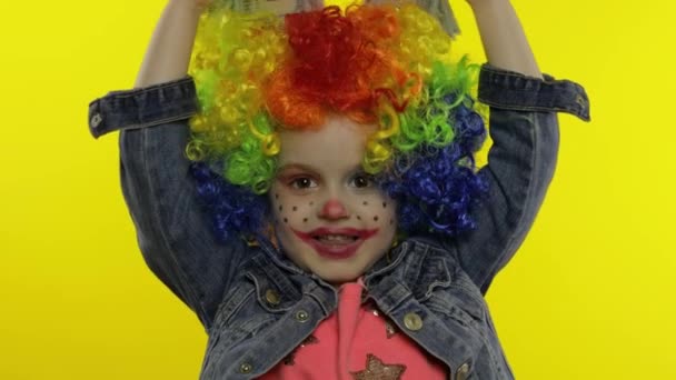 Kleines Kindermädchen Clown mit Perücke macht alberne Gesichter, Spaß mit Geldscheinen Dollar Cash — Stockvideo