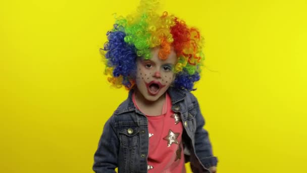 Pequena criança palhaço menina em peruca colorida fazendo caras bobas. A divertir-se, a cantar, a dançar. Halloween. — Vídeo de Stock