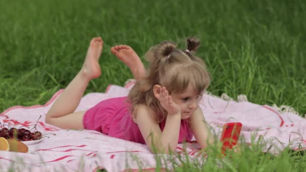 Helg på picknick. Flicka på gräs äng spela online-spel på mobiltelefon. Sociala nätverk, chattar — Stockvideo