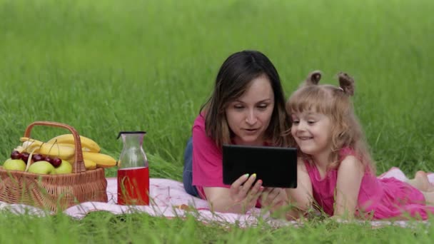 家庭周末野餐。女儿和妈妈在平板电脑上玩网络游戏。聊天室 — 图库视频影像