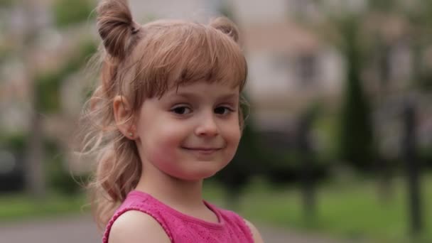 Niña contra el fondo borroso de la calle de la ciudad. Emociones alegres, positivas, sonrisa — Vídeos de Stock