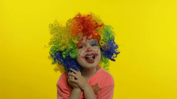 Mała dziewczynka klaun w kolorowe peruka robi głupie miny, zabawy, uśmiech, taniec. Halloween — Zdjęcie stockowe