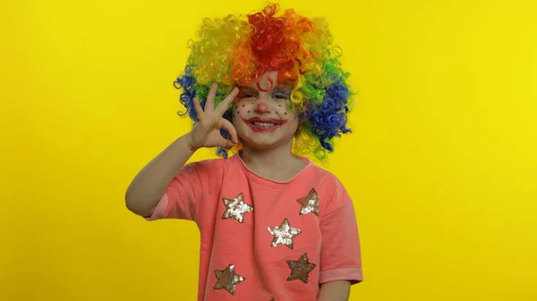 カラフルなウィッグの中で小さな子供の女の子ピエロは、楽しさ、笑顔、ダンスを持って、愚かな顔を作ります。ハロウィン — ストック写真