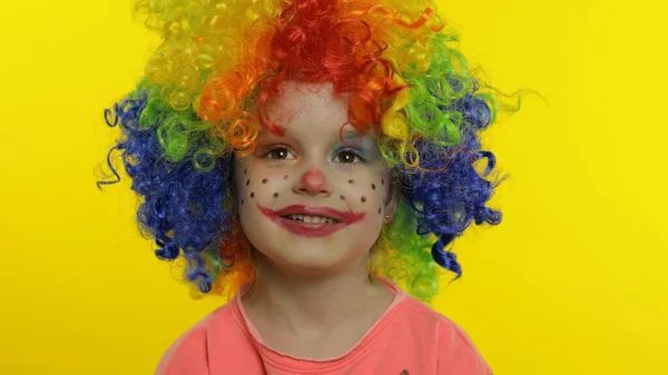 Kleine Kinderclownin mit bunter Perücke, die alberne Gesichter macht, Spaß hat, lächelt, tanzt. Halloween — Stockfoto