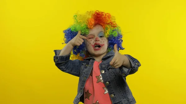 Niña payaso en peluca colorida haciendo caras tontas. Divertirse, sonreír, bailar. Halloween — Foto de Stock