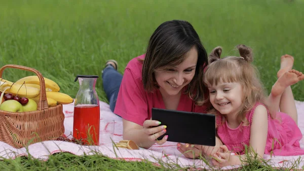 Családi hétvégi piknik. Lány gyermek lány anya játék online játékok tabletta. Beszélgetés — Stock Fotó